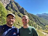 De to forskerne avbildet i solskinn med grønne fjellsider bak seg.