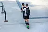 Two people ride electric scooters on a concrete surface in Oslo city centre.