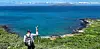 Galápagos National Park guide on a hillside overlooking the ocean and shoreline on Santa Cruz Island.