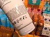 Close-up of a large cosmetic bottle in front of shelves of assorted beauty products.