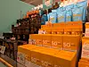 Stacked skincare products in orange and blue packaging displayed on a shop shelf.