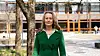 Merete Glenne Øie stands outside a modern university building with trees in the foreground.