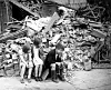 Three children sitting in front of a large pile of bricks and ruins in East London in 1940.