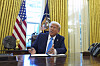 Donald Trump sitter ved skrivebordet i Det ovale kontor og snakker mens han signerer dokumenter.