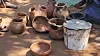 Assorted clay jars, bowls and a lidded container arranged on the ground.