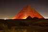 Kheopspyramiden i Giza opplyst i oransje lys om natten.