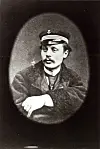 Black-and-white portrait of a young man in a naval officer’s cap and coat seated in a studio.