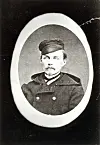 Old black-and-white portrait of a young man in uniform with a cap in an oval frame.