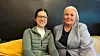Two women sat on a yellow couch