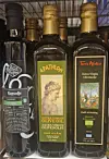 Three bottles of oils with different labels standing on a store shelf.