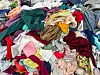 Heap of mixed discarded clothing and textiles in a recycling facility.
