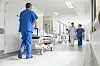Hospital staff push a stretcher down a bright corridor with a patient and doctors nearby.
