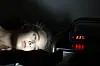 Teenage girl in bed at night looking at a smartphone beside a digital clock.
