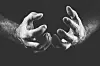 Black-and-white close-up of two open hands against a dark background.