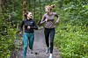 To kvinner løper på en skogssti omgitt av grønn skog i Oslo.