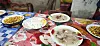 Bowls of lentil soup and plates of pasta, cheese and maize on a patterned table in a local restaurant.