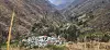 Aerial view of Tupe village in a mountain valley with steep hills and patchy green vegetation.
