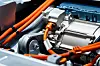 Close-up of an electric car motor with orange high-voltage cables and metallic components.