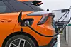 Orange electric car connected to a charging station in a parking area.
