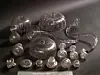Shiny metallic bowls, vessels and linked decorative pieces displayed on a dark background.