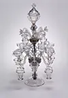 Decorative clear glass chandelier with multiple arms on a plain light background.