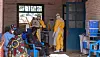 Health workers in protective suits prepare medical supplies inside a clinic doorway in Mongbwalu, DR Congo.