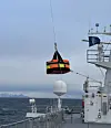 A vessel deck with suspended towing equipment being lifted over the sea during the EMTOW project.