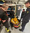 Rescue team members stand around an open helibag filled with coiled rope and equipment in a garage.