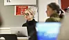 Office scene with VGS signage, two people at laptops and blurred figures in the foreground.