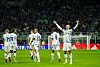 Erling Braut Haaland spreads his arms out on the football pitch, five other teammates are seen with their backs to him. In the background, a stadium full of spectators get can be seen.
