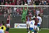 A goalkeeper in a green jersey jumps up and catches the football in front of the goal. Behind the goal are Norwegian football supporters with scarves in red, white and blue. Around the goal are Norwegian and Italian players.