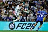 Football player Lionel Messi jumps in the air with the ball on his left foot. An Icelandic player runs ahead of him. The crowd can be seen in the background.