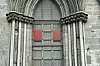 Red oak test panels mounted on a cathedral door framed by carved stonework.