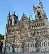 Nidaros Cathedral’s detailed west front with tall towers and grey portal doors in Trondheim.