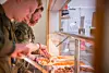 Soldiers in a mess hall serve food from a buffet counter at Ørland Air Station.