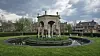 Stone pavilion in a landscaped green in Economy, Pennsylvania, with historic buildings under a cloudy sky.