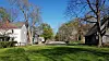 Tree-lined historic street in New Harmony, Indiana, with old buildings and a grassy foreground.