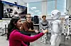 Students in a computer science lab interact with a white humanoid robot named Pepper.