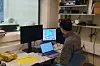 Person seated at a desk using two laptops and monitors during a brain imaging study.