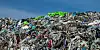 A huge pile of discarded clothing and textiles stacked in a landfill under a blue sky.