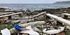 Plastic waste and broken debris scattered on a rocky beach beside the sea.