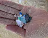 A hand smalling small colourful plastic pieces on a sandy beach