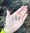 A hand holding three small arrowheads