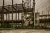 Industrial pipes and metal framework behind fencing at a utility site.