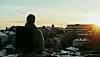 A man seen from behind looks out over the city.