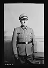 A uniformed officer stands in a black-and-white photograph.