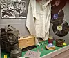 Display cases containing a white uniform, antique objects, a camera, and a large vinyl record.