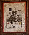 A framed certificate featuring an image of the Tirpitz, a medal, and handwritten signatures on a light background.