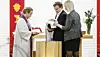 A priest pours water over a child at the baptismal font while the parents stand beside them in Byåsen Church.