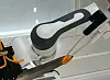 A robotic arm in a laboratory grasps a small object with a gripper in a test setup.